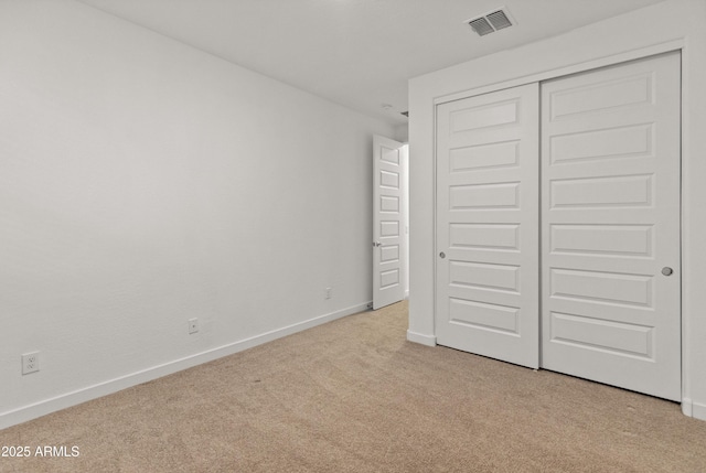 unfurnished bedroom with baseboards, visible vents, a closet, and light colored carpet