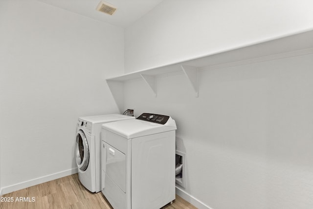 laundry area with light wood-style floors, washer and dryer, laundry area, and baseboards