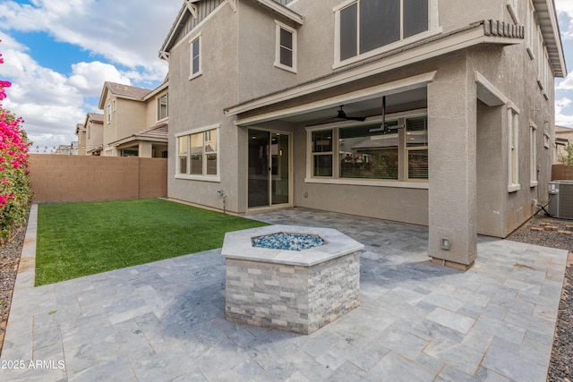 view of patio featuring a ceiling fan, an outdoor fire pit, cooling unit, and fence