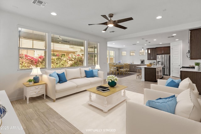 living area featuring baseboards, ceiling fan, visible vents, and recessed lighting