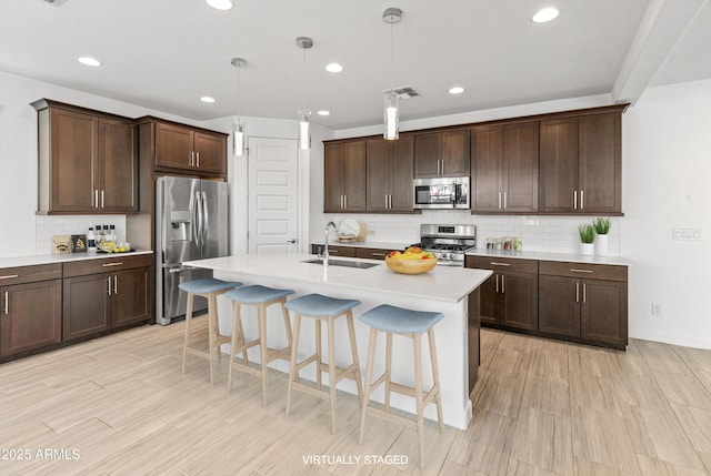 kitchen with stainless steel appliances, visible vents, a sink, and dark brown cabinetry