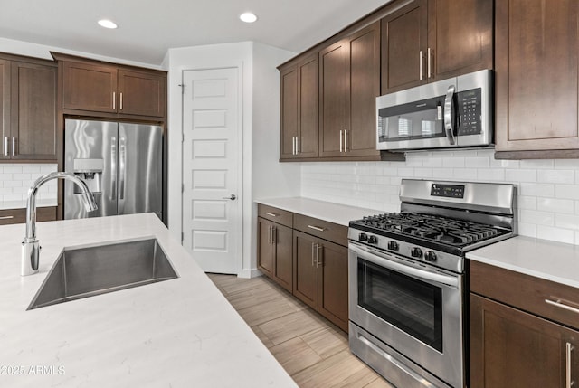 kitchen with dark brown cabinetry, appliances with stainless steel finishes, light countertops, and a sink