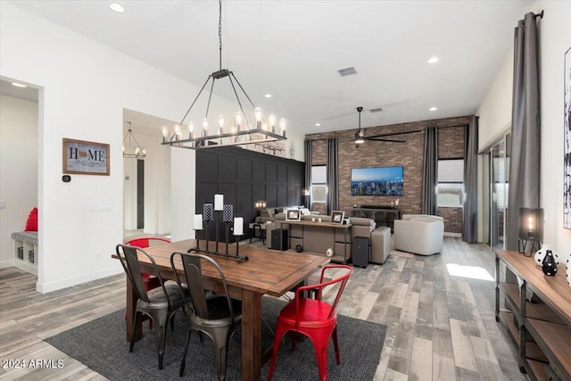 dining space with a fireplace, light hardwood / wood-style floors, ceiling fan, and brick wall