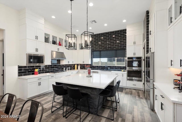 kitchen featuring a kitchen island, white cabinets, a kitchen bar, and appliances with stainless steel finishes