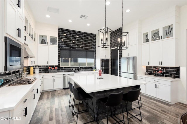 kitchen featuring a breakfast bar area, backsplash, dark hardwood / wood-style flooring, a center island, and stainless steel appliances