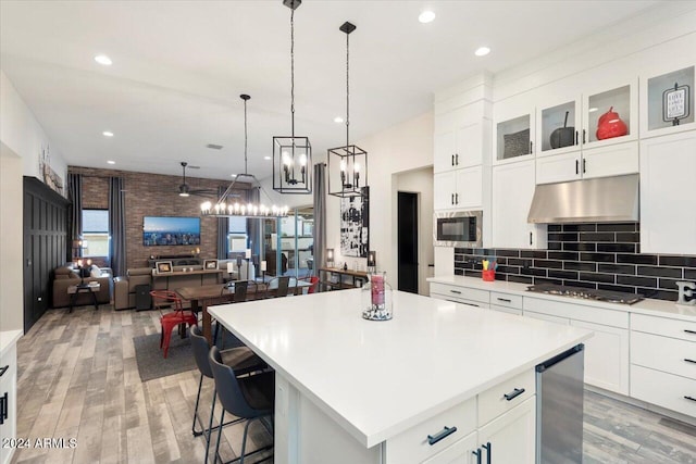 20428 W Elm Dr, Buckeye, AZ 85396 - kitchen with under cabinet range hood, light wood finished floors, light countertops, a kitchen island, and recessed lighting