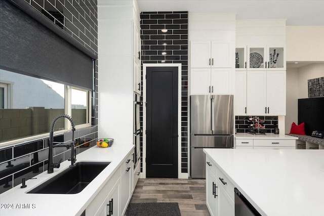 kitchen with stainless steel refrigerator, white cabinetry, sink, decorative backsplash, and light hardwood / wood-style flooring