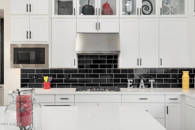 kitchen with built in microwave, white cabinetry, stainless steel gas stovetop, and backsplash