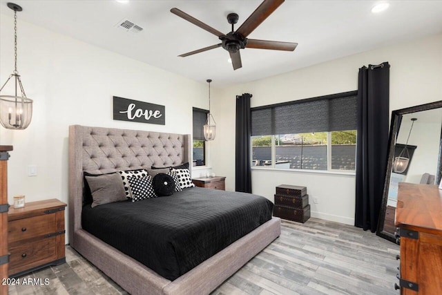 bedroom featuring ceiling fan with notable chandelier and wood-type flooring