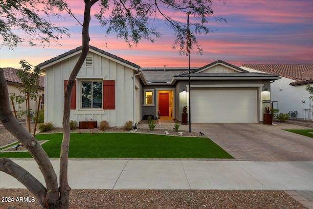 20428 W Elm Dr, Buckeye, AZ 85396 - single story home featuring board and batten siding, decorative driveway, solar panels, an attached garage, and a yard