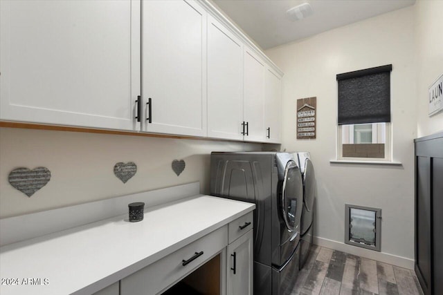 laundry room featuring dark wood-type flooring, cabinets, and washer and clothes dryer