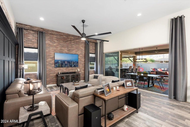 living room featuring ceiling fan, brick wall, and light wood-type flooring