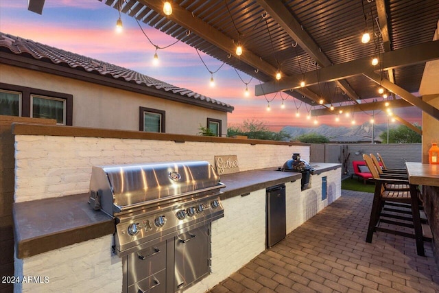 20428 W Elm Dr, Buckeye, AZ 85396 - patio terrace at dusk with area for grilling, grilling area, a bar, and fence