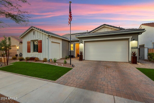 ranch-style house featuring a garage and a lawn