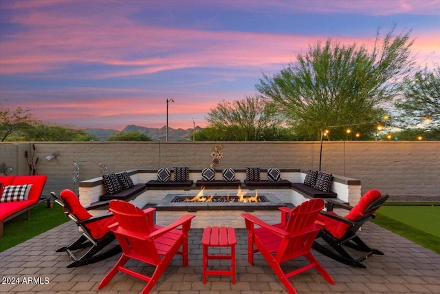 20428 W Elm Dr, Buckeye, AZ 85396 - patio terrace at dusk featuring a putting green, a fenced backyard, and an outdoor living space with a fire pit