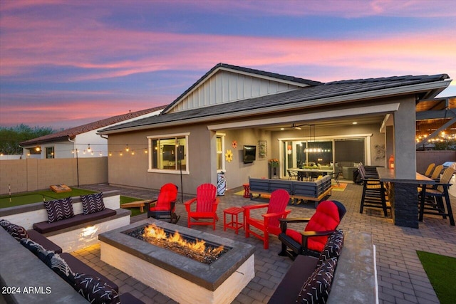 patio terrace at dusk featuring ceiling fan and an outdoor living space with a fire pit