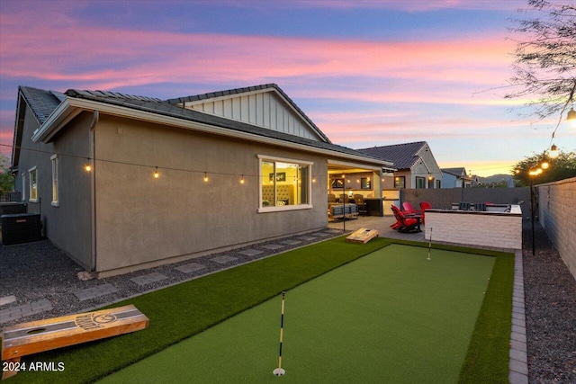 back house at dusk featuring central AC unit and a patio area