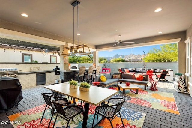 view of patio featuring ceiling fan, an outdoor kitchen, outdoor lounge area, and a mountain view