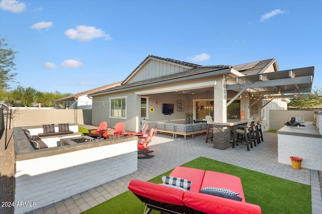 rear view of house featuring a patio, an outdoor kitchen, and an outdoor living space with a fire pit