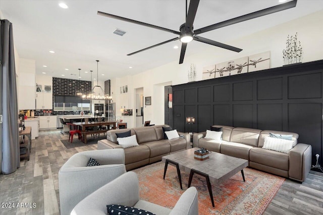 living room with ceiling fan with notable chandelier and light hardwood / wood-style floors