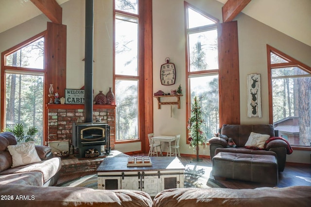 living room featuring a wood stove, beam ceiling, wood finished floors, and a towering ceiling