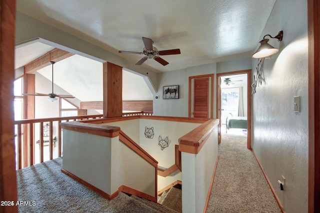 hallway with carpet floors, a wealth of natural light, lofted ceiling with beams, and an upstairs landing