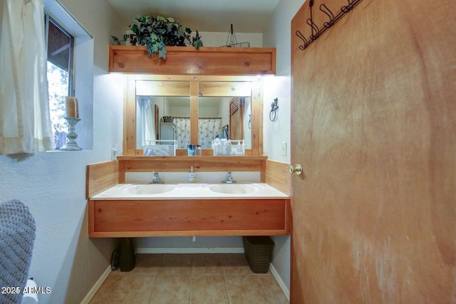 bathroom with tile patterned flooring, a sink, and baseboards