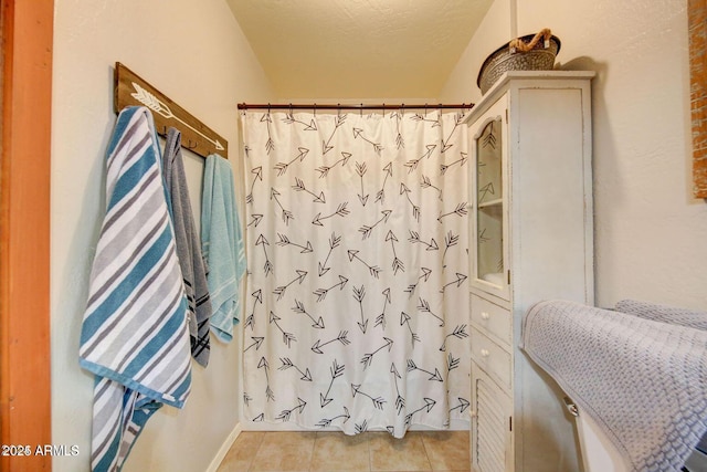 bathroom with tile patterned flooring, a textured ceiling, and curtained shower