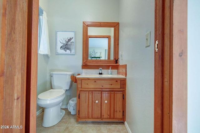 half bathroom with tile patterned flooring, baseboards, vanity, and toilet