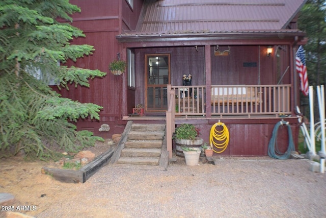 view of exterior entry with covered porch and metal roof