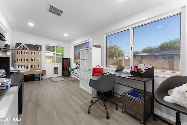 home office with a wealth of natural light, light hardwood / wood-style floors, and vaulted ceiling