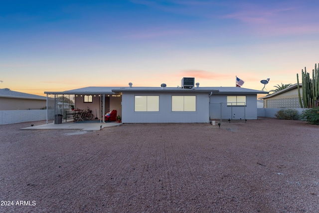 back house at dusk featuring central AC and a patio area