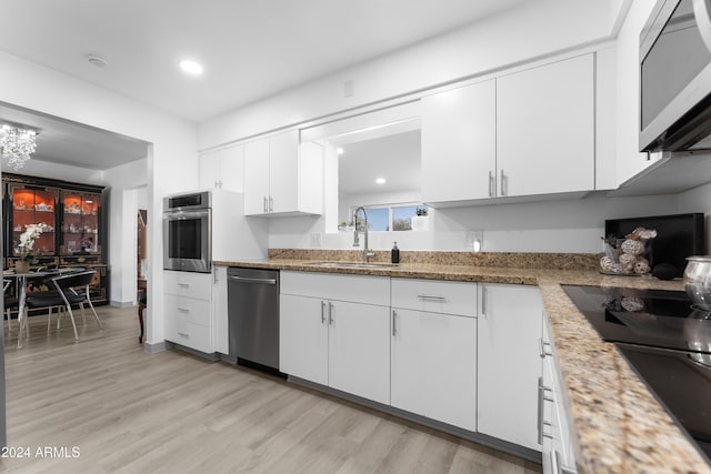 kitchen featuring light stone countertops, white cabinetry, sink, stainless steel appliances, and light hardwood / wood-style flooring