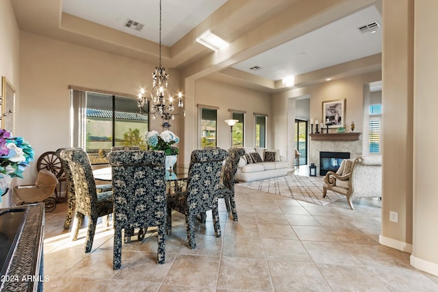 tiled dining room featuring a healthy amount of sunlight, a raised ceiling, and a notable chandelier