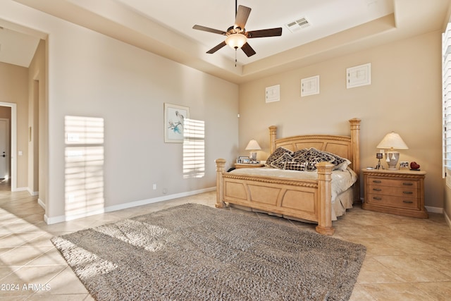 bedroom featuring light tile patterned floors, ceiling fan, and a raised ceiling