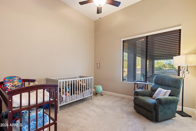 carpeted bedroom featuring a nursery area, lofted ceiling, and ceiling fan