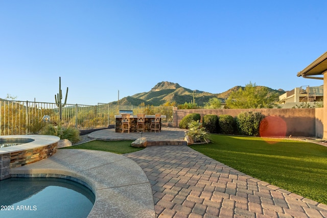 view of patio with a mountain view and a pool with hot tub