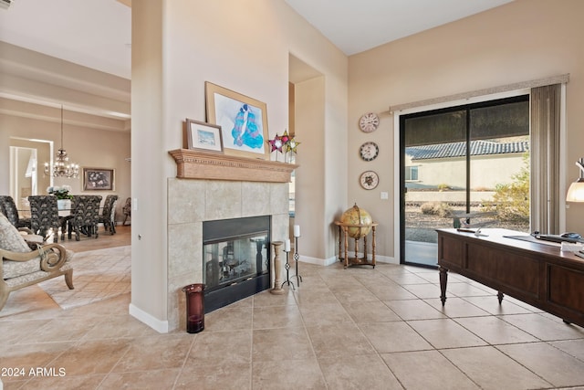 office space with a fireplace, light tile patterned flooring, and an inviting chandelier