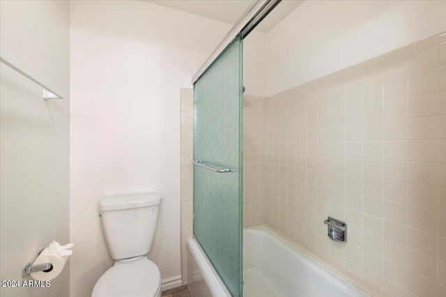 bathroom with enclosed tub / shower combo and toilet