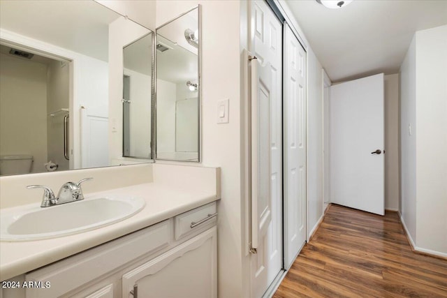 bathroom featuring hardwood / wood-style floors, vanity, toilet, and a shower