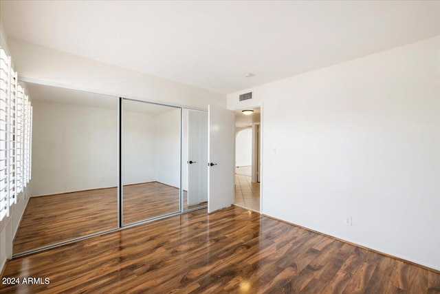 unfurnished bedroom featuring wood-type flooring and a closet