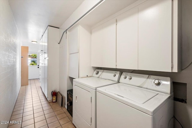 laundry room featuring cabinets, light tile patterned flooring, and separate washer and dryer