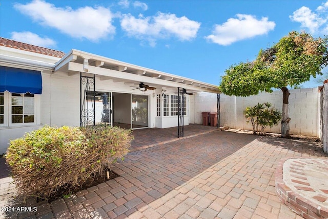 rear view of house featuring ceiling fan and a patio