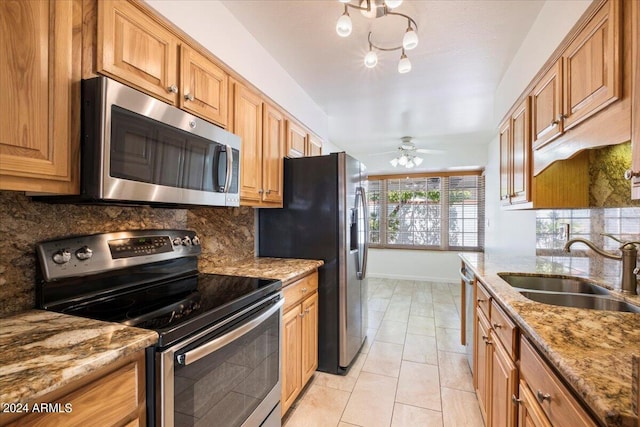 kitchen featuring ceiling fan, light stone counters, sink, tasteful backsplash, and appliances with stainless steel finishes