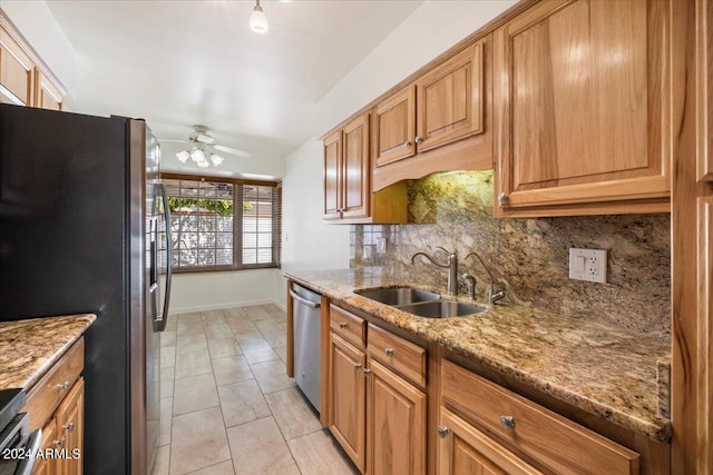 kitchen with sink, decorative backsplash, appliances with stainless steel finishes, light stone countertops, and ceiling fan