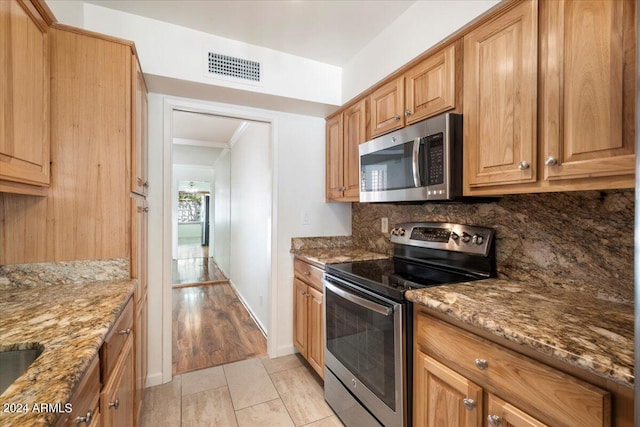 kitchen with stainless steel appliances, stone counters, decorative backsplash, and light hardwood / wood-style flooring