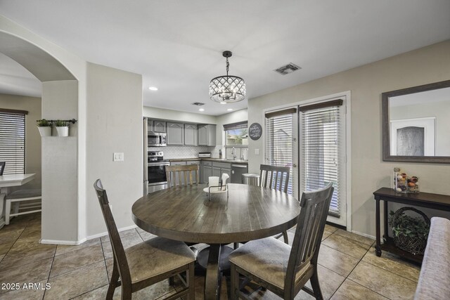 dining room featuring tile patterned flooring, a notable chandelier, arched walkways, and visible vents