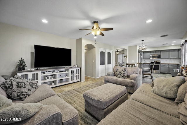 living area with visible vents, ceiling fan with notable chandelier, recessed lighting, arched walkways, and light tile patterned floors