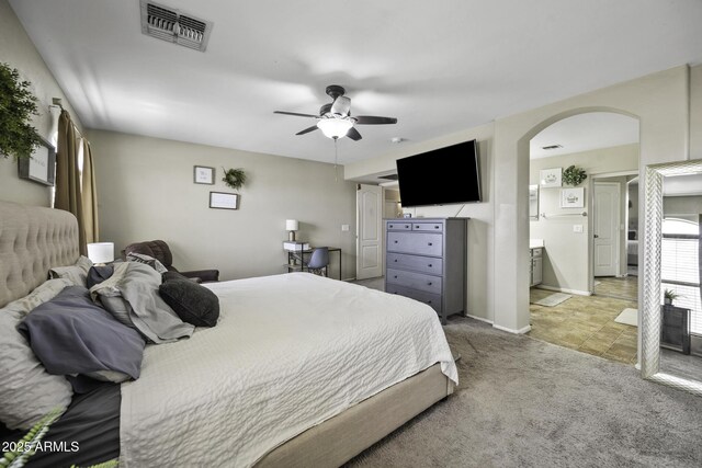 bedroom with a ceiling fan, baseboards, visible vents, arched walkways, and light colored carpet