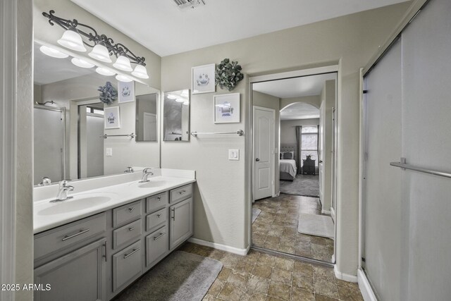 bathroom featuring double vanity, stone finish floor, baseboards, and a sink